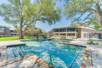A swimming pool surrounded by trees and a house in the background.